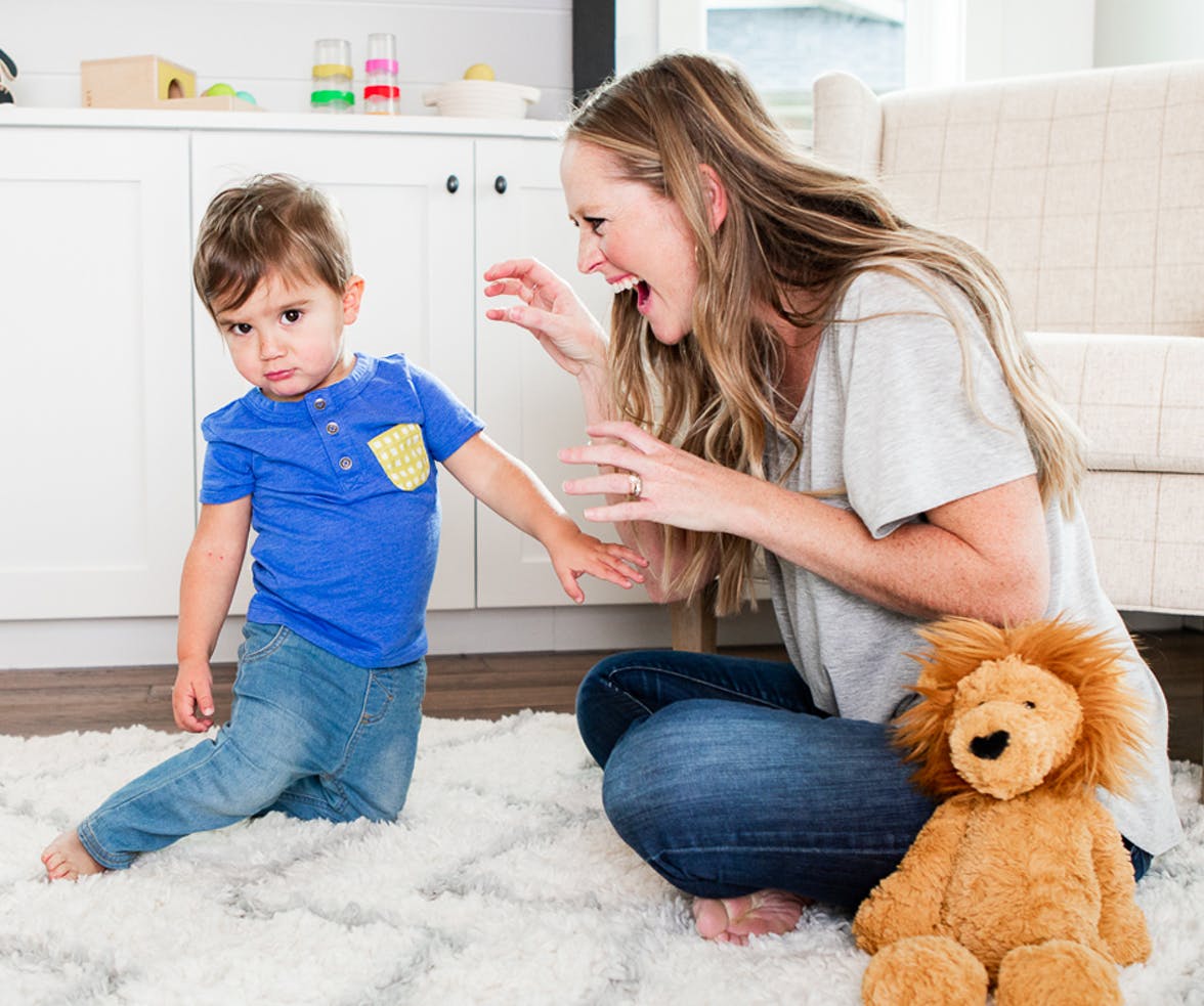 Woman roaring like a lion to a toddler next to a lion stuffed animal