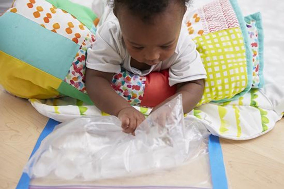 Baby playing with a plastic bag filled with ice cubes