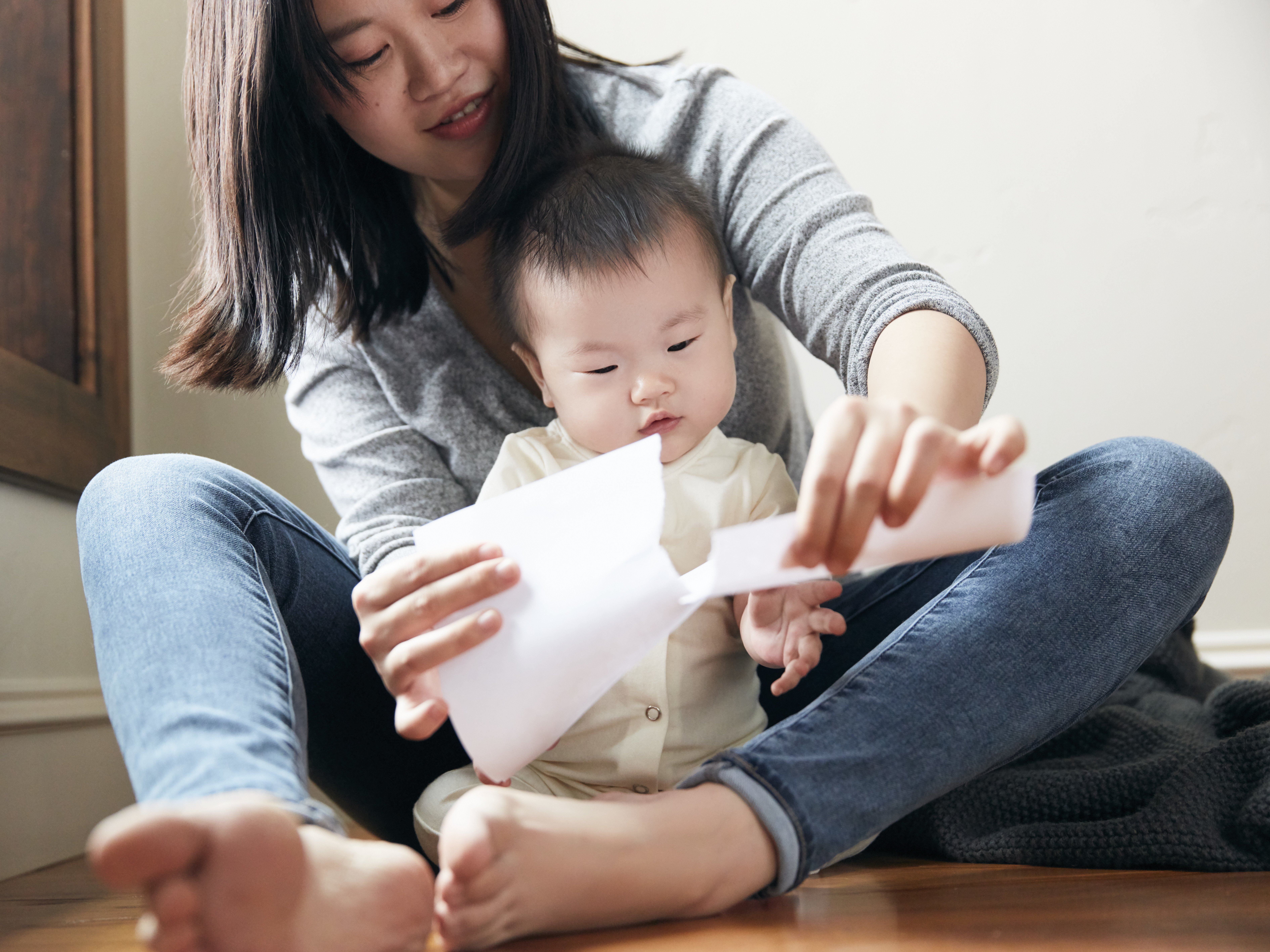 Woman ripping a piece of paper in front of a baby sitting in front of her