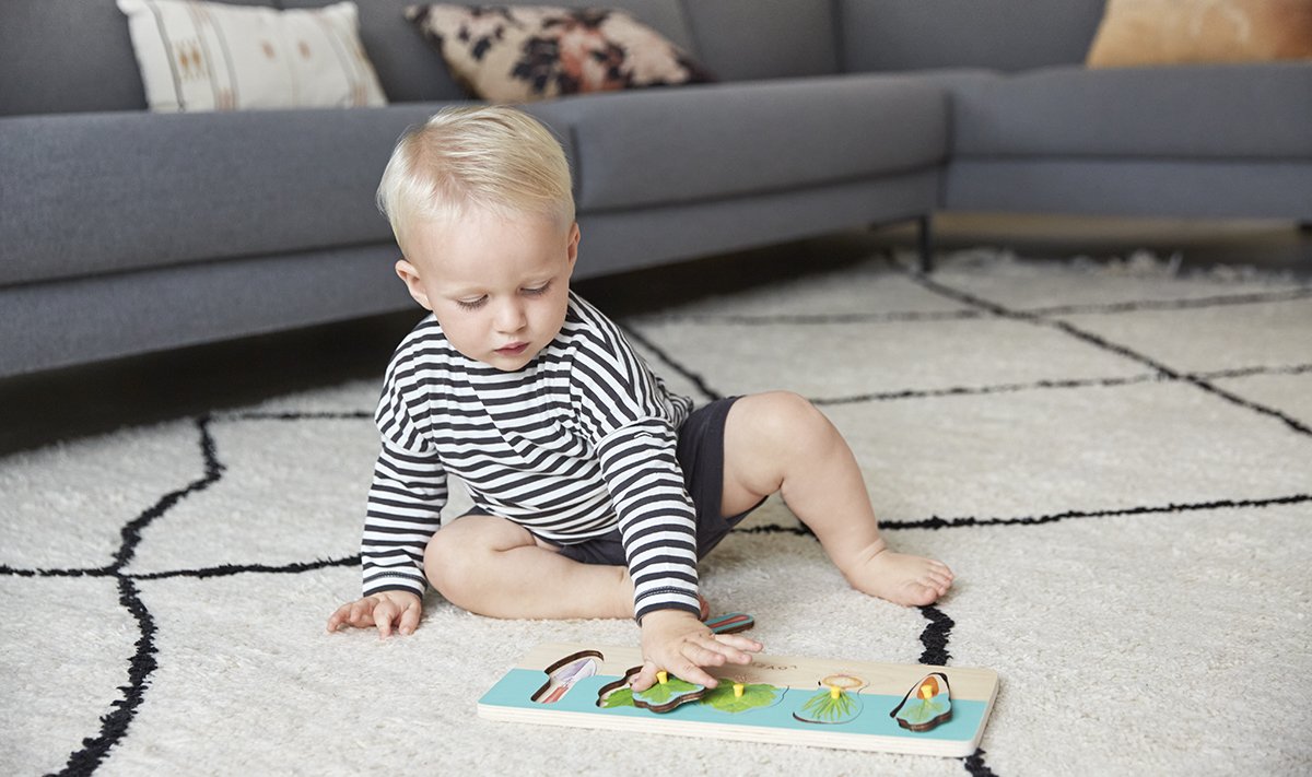 Toddler playing with a Community Garden puzzle by Lovevery