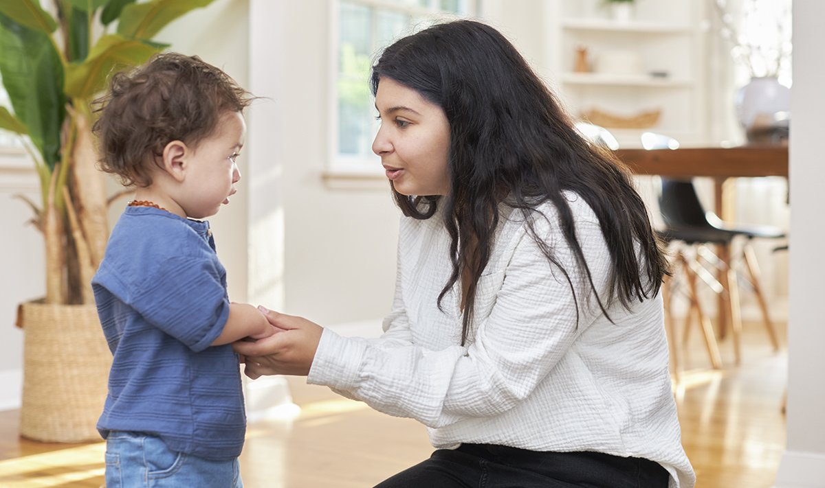 Woman holding a toddler's hand while looking at them.