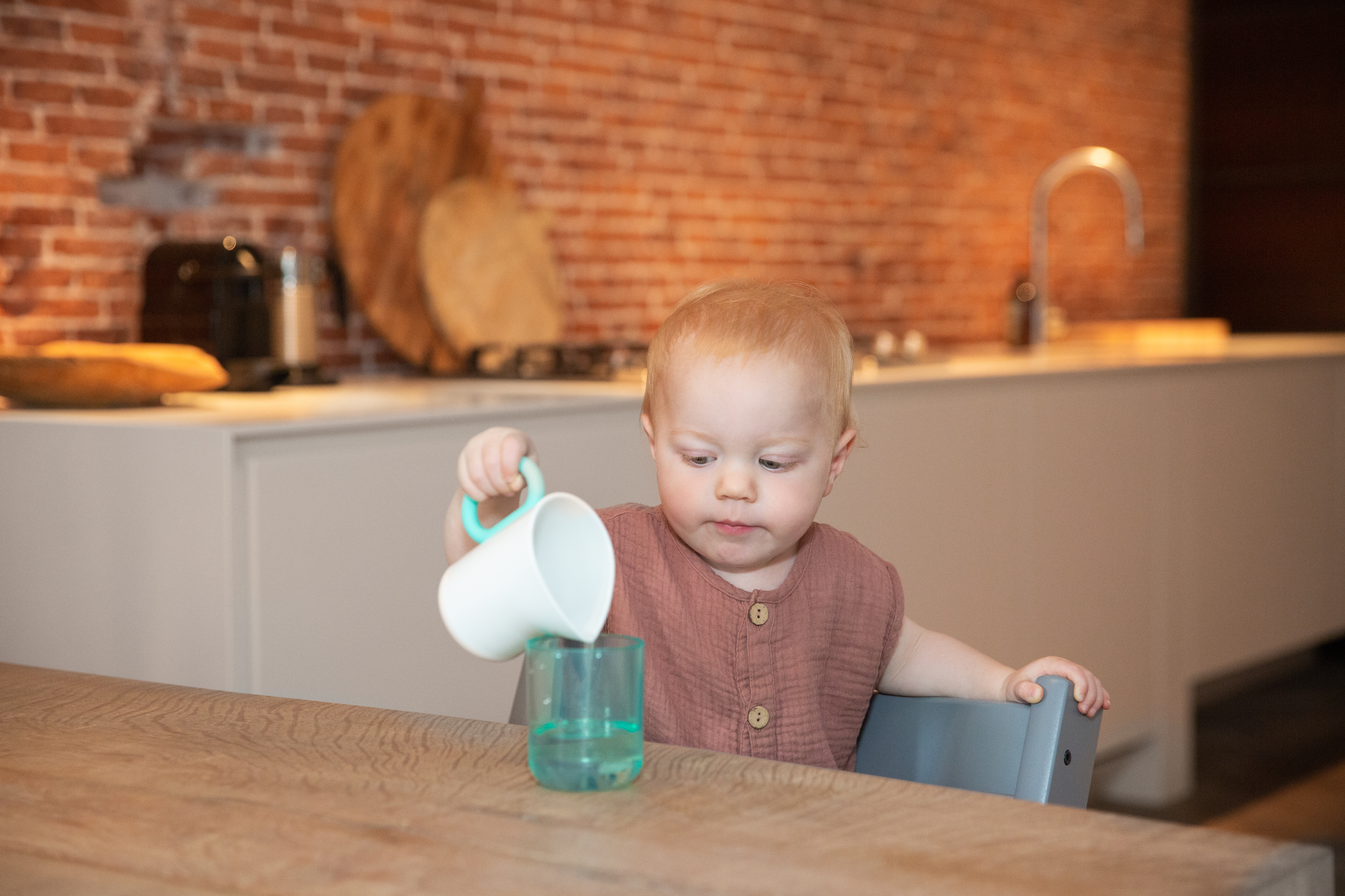 Toddler pouring water from the Grooved Pitcher by Lovevery