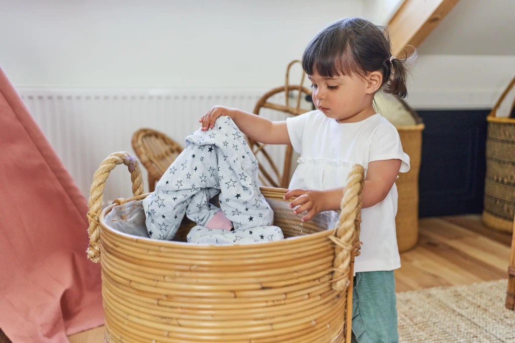 Child putting clothes in a laundry basket