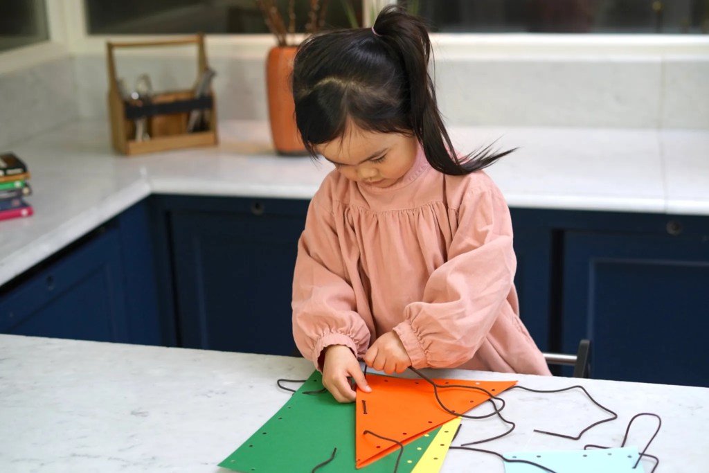 Child lacing paper together