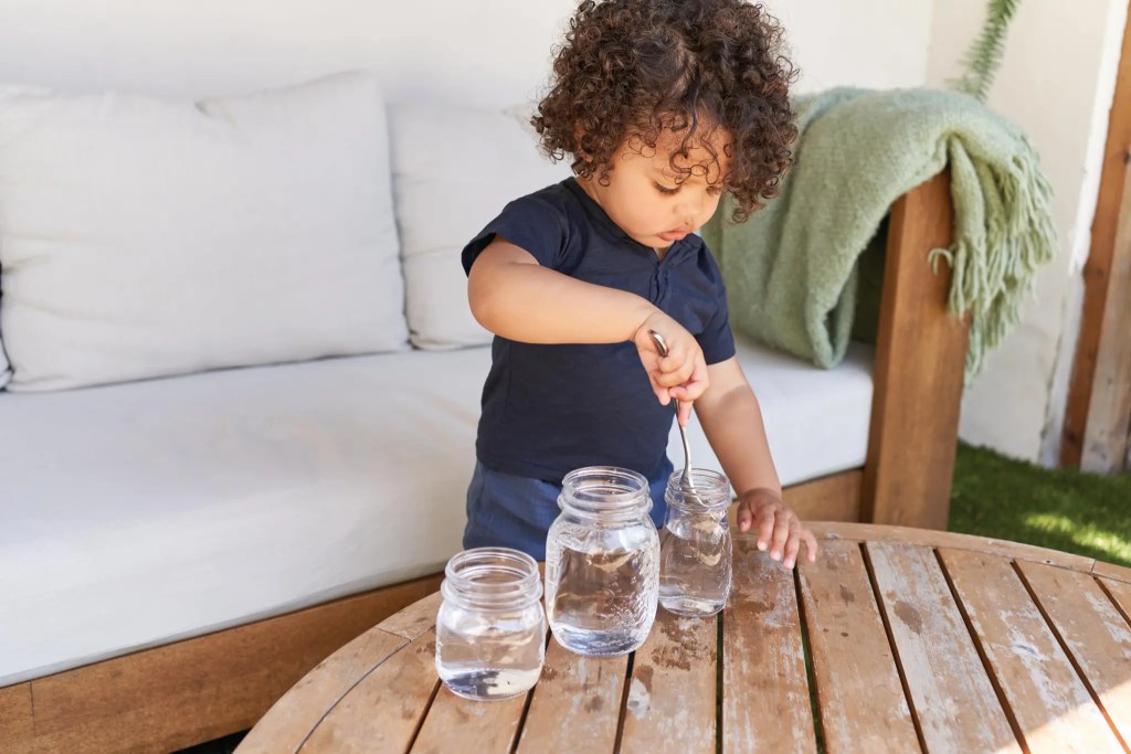 Child playing with water filled mason jars