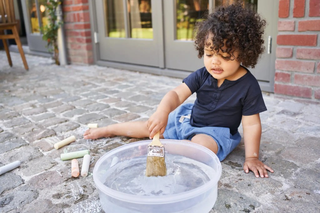 Child painting with water outside